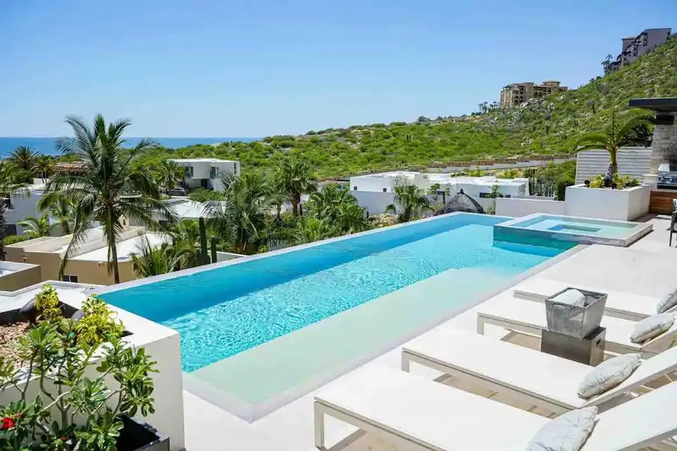 Casa Texas daytime infinity pool and lounge chairs overlooking Pedregal and the ocean